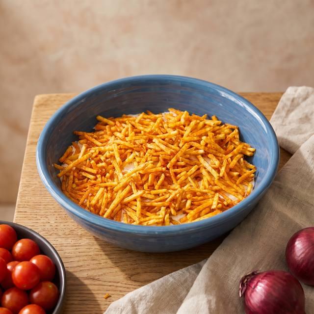 Chips-Salat mit knusprigen Chips Sticks in einer blauen Glasschüssel, daneben Tomaten und Kräuter – Pampered Chef® Rezept