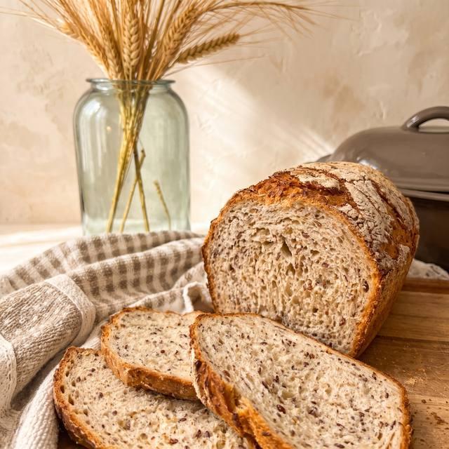 Aufgeschnittene Kernige Joghurtkruste mit sichtbaren Saaten in der Krume auf einem Holzbrett – Pampered Chef® Rezept
