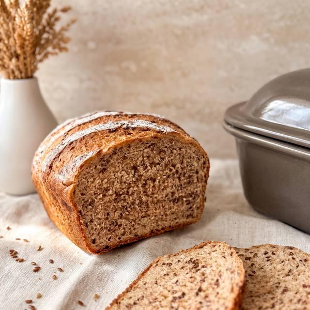 Aufgeschnittenes Leinsamenbrot mit Saatenkruste auf einem karierten Tuch – Pampered Chef® Rezept