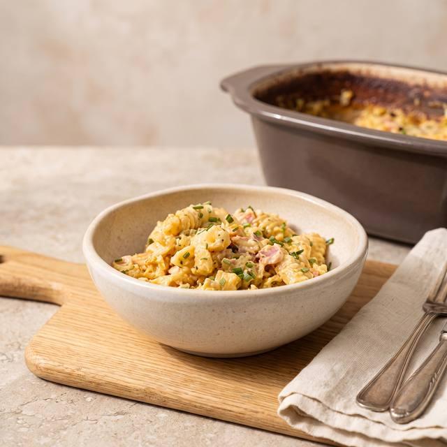 Cremiger Nudel-Schinken-Topf mit Schnittlauch bestreut in einer Schale, im Hintergrund der Pampered Chef® Kleine Ofenmeister