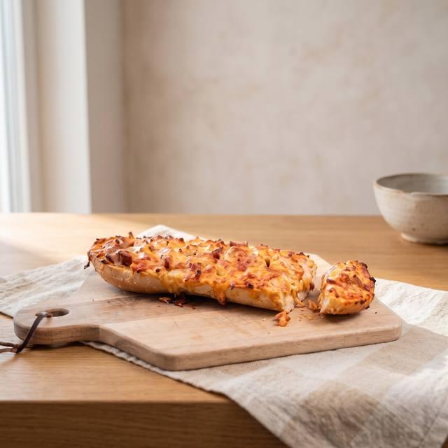 Überbackene Pizzabrötchen mit Wurst, Käse und Zwiebeln auf der Arbeitsfläche – Pampered Chef® Rezept
