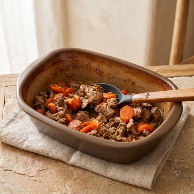 Putenbraten mit Möhren und Zwiebeln im Pampered Chef® Ofenmeister, mit einem Kochlöffel serviert