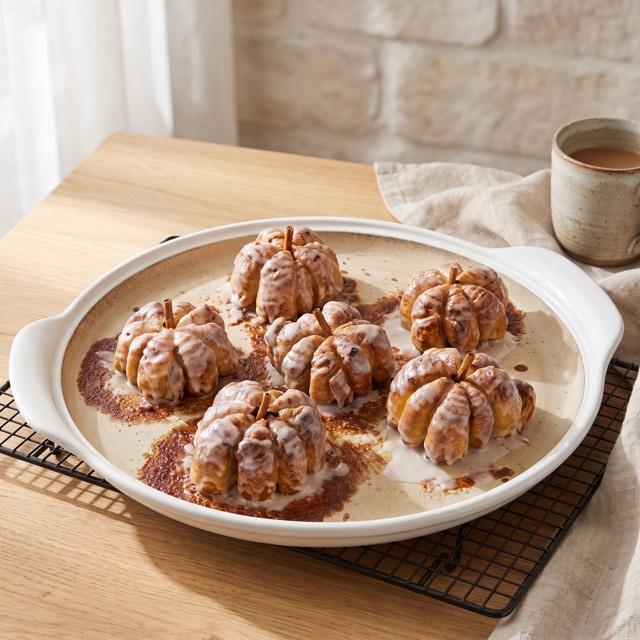 Sechs glasierte Zimtschnecken in Kürbisform mit Zimtstangen-Stängel auf dem weißen Großen runden Stein – Pampered Chef® Rezept
