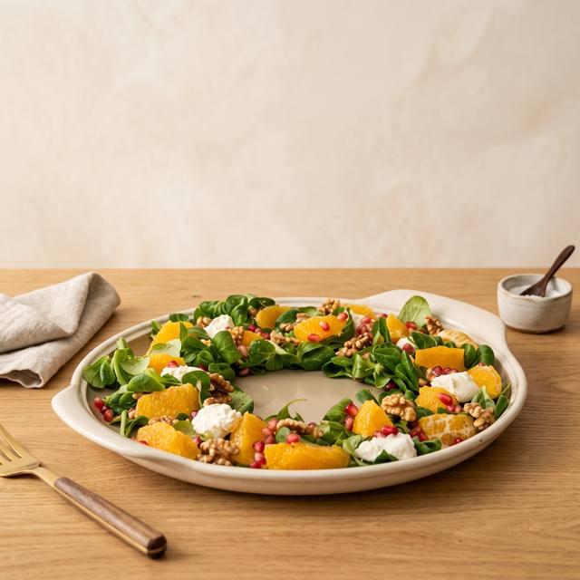 Wintersalat-Kranz aus Feldsalat, Orangen, Granatapfel, Walnüssen und Burrata auf einem runden Teller – Pampered Chef® Rezept